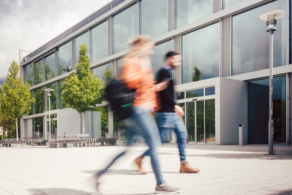 Blurred silhouette of students being busy on university campus in front of main building